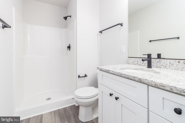 bathroom featuring vanity, hardwood / wood-style floors, toilet, and walk in shower