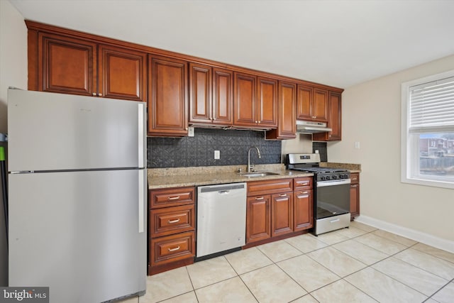 kitchen featuring appliances with stainless steel finishes, sink, decorative backsplash, light tile patterned floors, and light stone counters