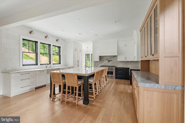 kitchen with white cabinetry, a large island, high end range, glass insert cabinets, and custom range hood