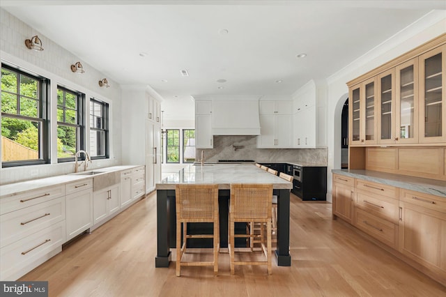 kitchen with custom range hood, a kitchen island, glass insert cabinets, and white cabinets