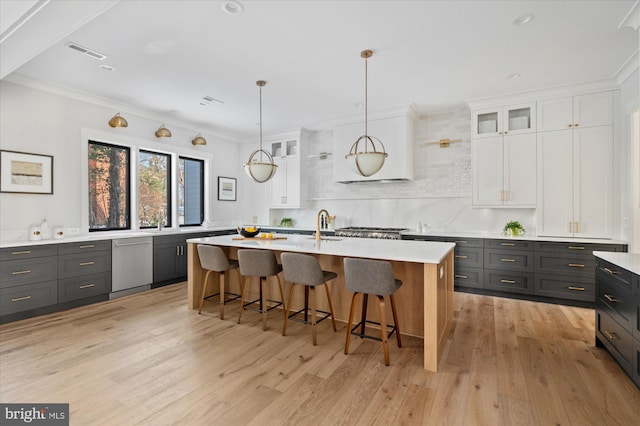 kitchen with an island with sink, glass insert cabinets, white cabinets, and light countertops