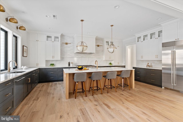 kitchen with glass insert cabinets, light countertops, stainless steel built in fridge, and white cabinetry