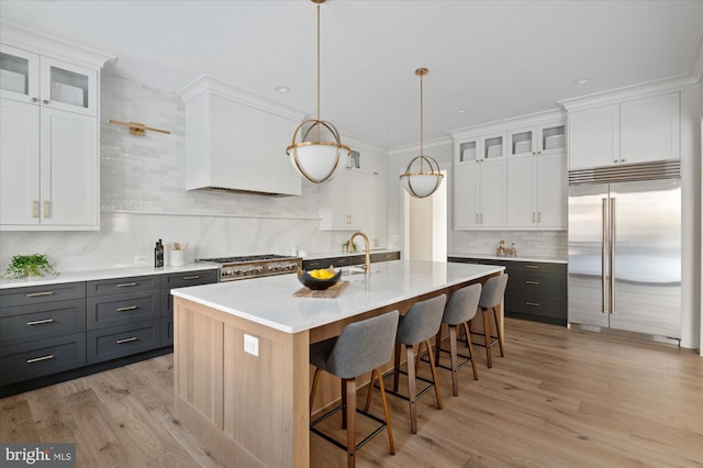 kitchen with light countertops, appliances with stainless steel finishes, an island with sink, and white cabinetry