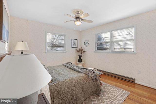 bedroom with a baseboard radiator, hardwood / wood-style floors, and ceiling fan