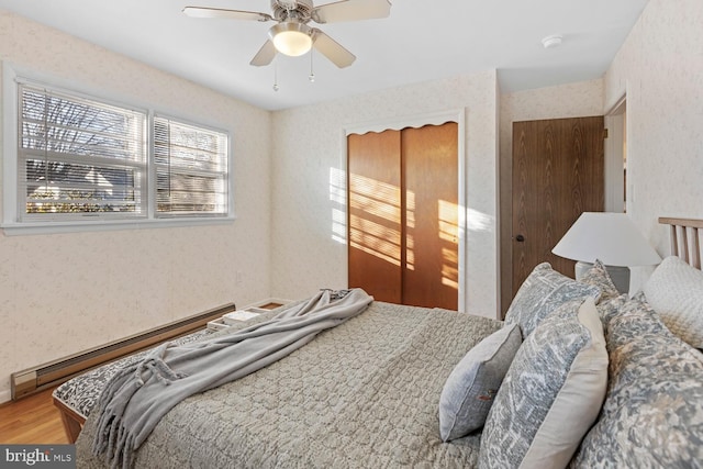 bedroom featuring ceiling fan, a baseboard radiator, and wood-type flooring