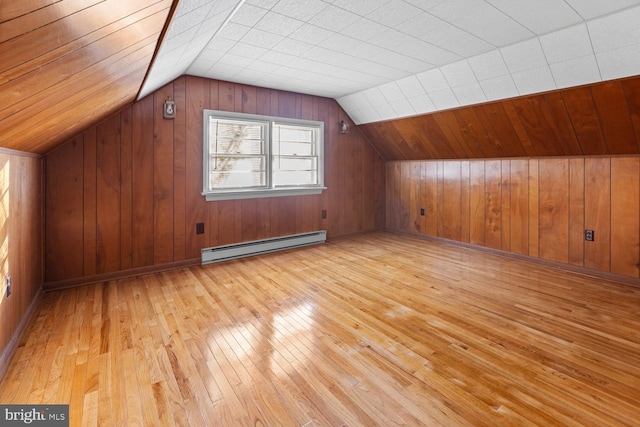 additional living space featuring a baseboard radiator, wood walls, vaulted ceiling, and light wood-type flooring