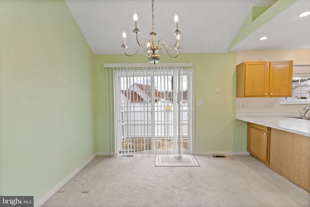 unfurnished dining area featuring lofted ceiling, sink, light carpet, and an inviting chandelier