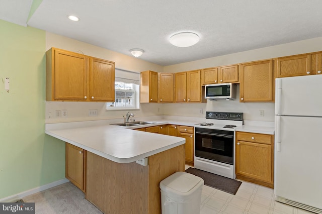 kitchen with range with electric stovetop, white fridge, sink, and kitchen peninsula