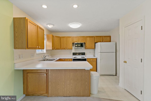 kitchen featuring electric range oven, sink, kitchen peninsula, and white fridge