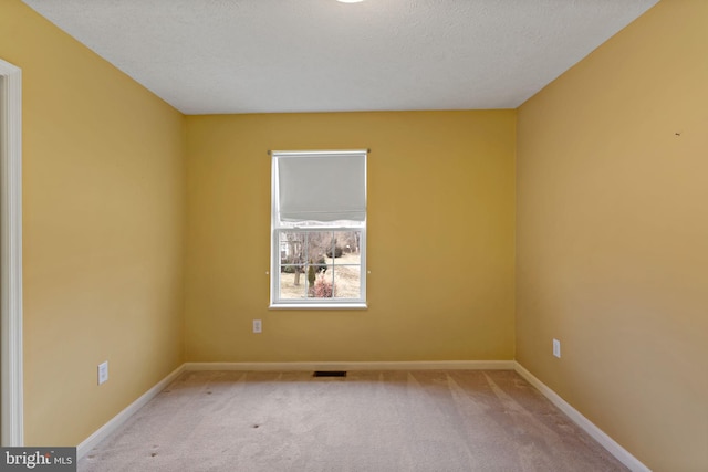 carpeted empty room featuring a textured ceiling