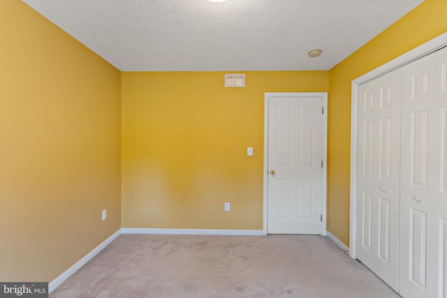 spare room featuring light carpet and a textured ceiling