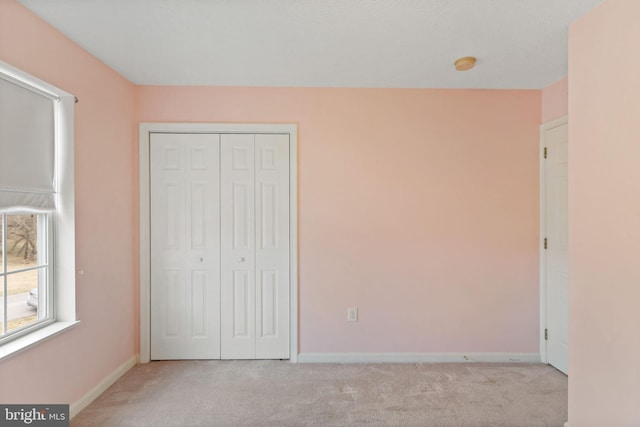 unfurnished bedroom with light carpet and a closet