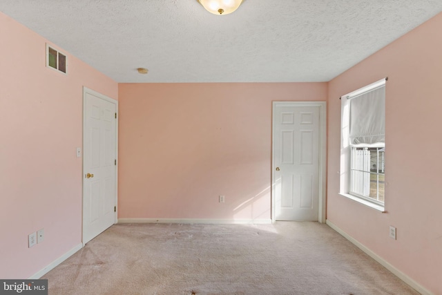 empty room with light colored carpet and a textured ceiling