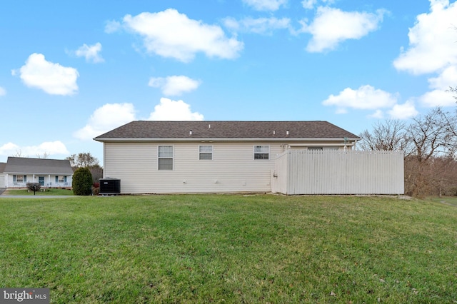 back of property with central AC unit and a lawn