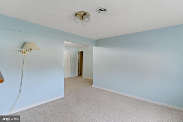 spare room with light carpet and a textured ceiling