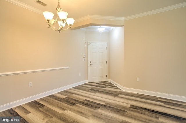 unfurnished room featuring hardwood / wood-style floors, crown molding, and a chandelier