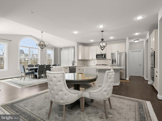 dining room with dark wood-type flooring, sink, a chandelier, and vaulted ceiling