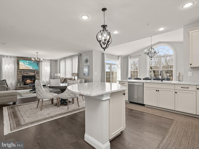 kitchen featuring white cabinetry, sink, stainless steel dishwasher, and hanging light fixtures