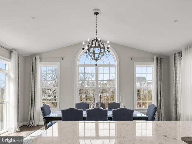 dining room with vaulted ceiling, a healthy amount of sunlight, and a notable chandelier