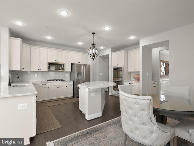 kitchen featuring sink, white cabinetry, decorative light fixtures, a center island, and stainless steel appliances