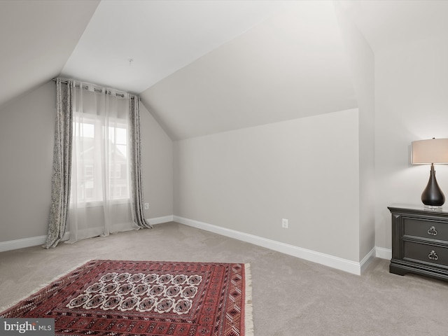 additional living space featuring lofted ceiling and light carpet