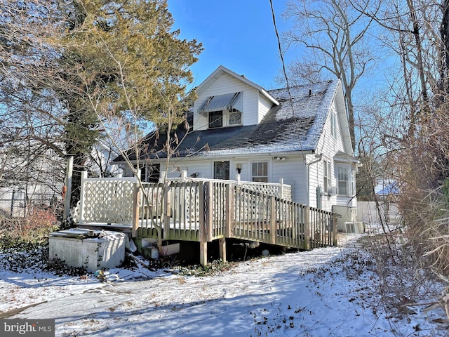 snow covered rear of property with a deck