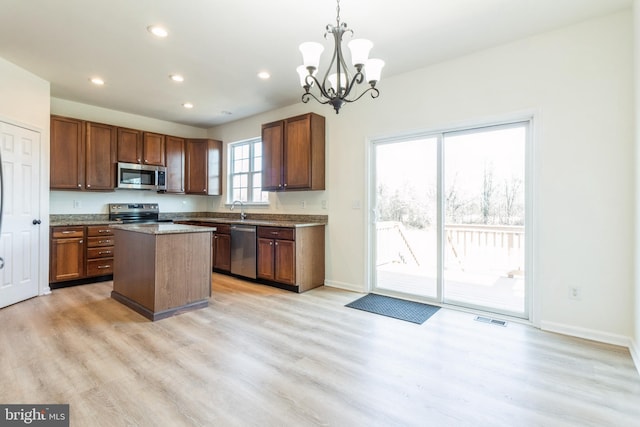 kitchen with sink, decorative light fixtures, a center island, light wood-type flooring, and stainless steel appliances