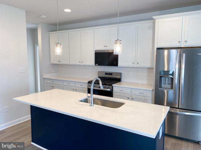 kitchen with white cabinetry, wood-type flooring, hanging light fixtures, an island with sink, and stainless steel appliances