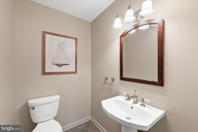 bathroom with baseboards, a sink, toilet, and tile patterned floors