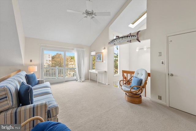 carpeted living room featuring ceiling fan, high vaulted ceiling, and a skylight