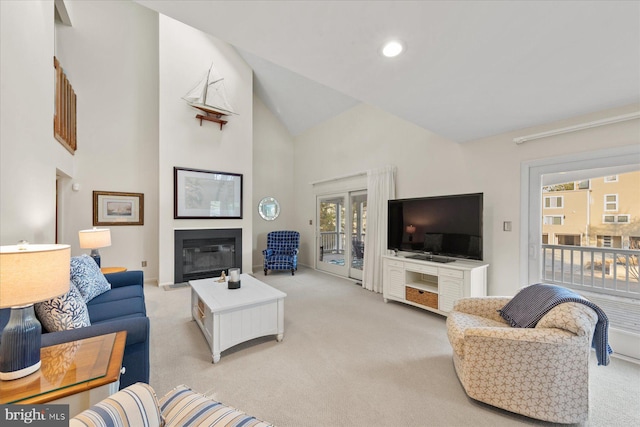 living room with light carpet, plenty of natural light, high vaulted ceiling, and a glass covered fireplace