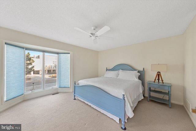 carpeted bedroom featuring a ceiling fan, visible vents, a textured ceiling, and baseboards