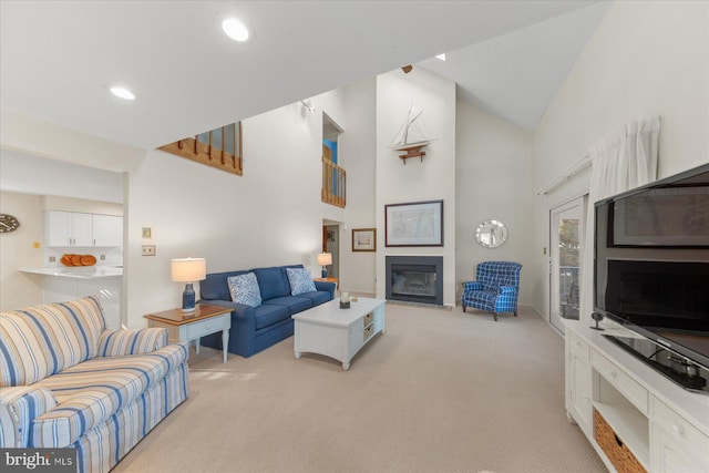 living room featuring high vaulted ceiling, recessed lighting, a large fireplace, and light colored carpet