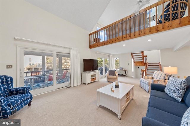 living area featuring a towering ceiling, recessed lighting, stairway, and light colored carpet