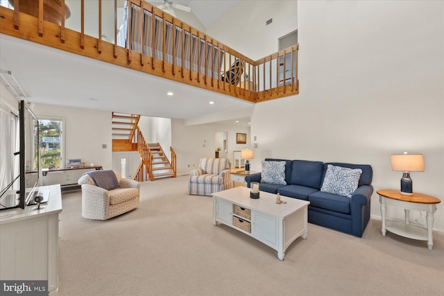 living area featuring light colored carpet, a towering ceiling, baseboards, and stairs