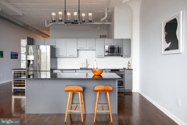 kitchen featuring a breakfast bar, sink, appliances with stainless steel finishes, dark hardwood / wood-style flooring, and backsplash