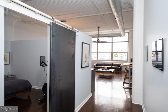 hallway with a barn door and dark wood-type flooring