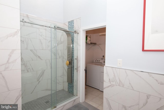 bathroom with washer / dryer, a shower with door, and tile patterned floors