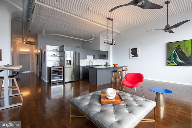 living room with wine cooler, dark wood-type flooring, sink, ceiling fan, and a high ceiling