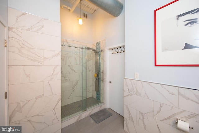 bathroom featuring a shower with shower door and tile walls