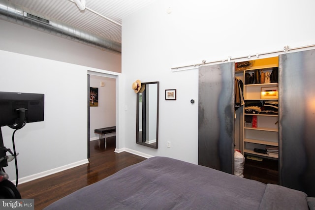 bedroom featuring dark wood-type flooring, a walk in closet, a barn door, and a closet