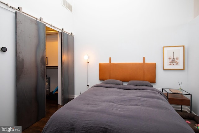 bedroom featuring dark hardwood / wood-style flooring and a barn door