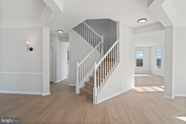 stairs with hardwood / wood-style flooring and crown molding