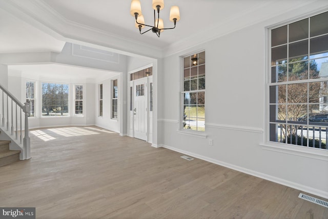 entryway featuring hardwood / wood-style flooring, ornamental molding, and a chandelier