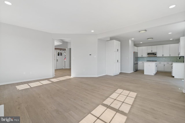 unfurnished living room with light wood-type flooring and sink