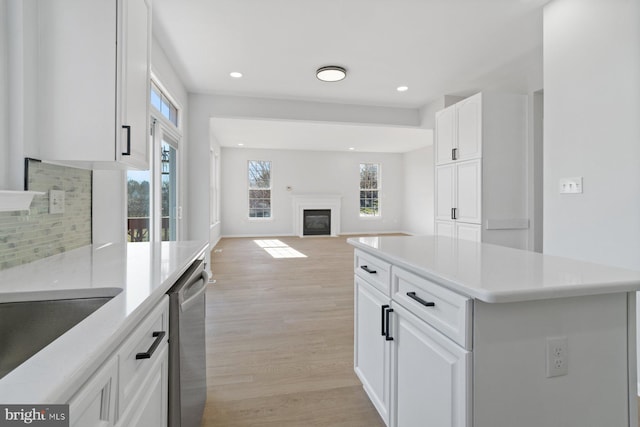 kitchen with a center island, white cabinetry, light hardwood / wood-style flooring, and stainless steel dishwasher