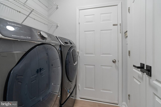 clothes washing area featuring washing machine and clothes dryer and wood-type flooring