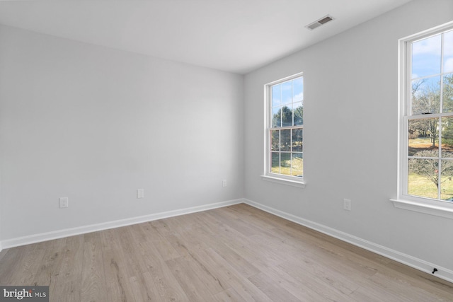 empty room with light hardwood / wood-style floors and a healthy amount of sunlight