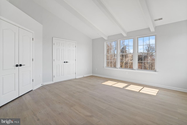 unfurnished bedroom with lofted ceiling with beams and light hardwood / wood-style floors