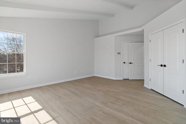 unfurnished bedroom featuring light wood-type flooring, a closet, and vaulted ceiling with beams